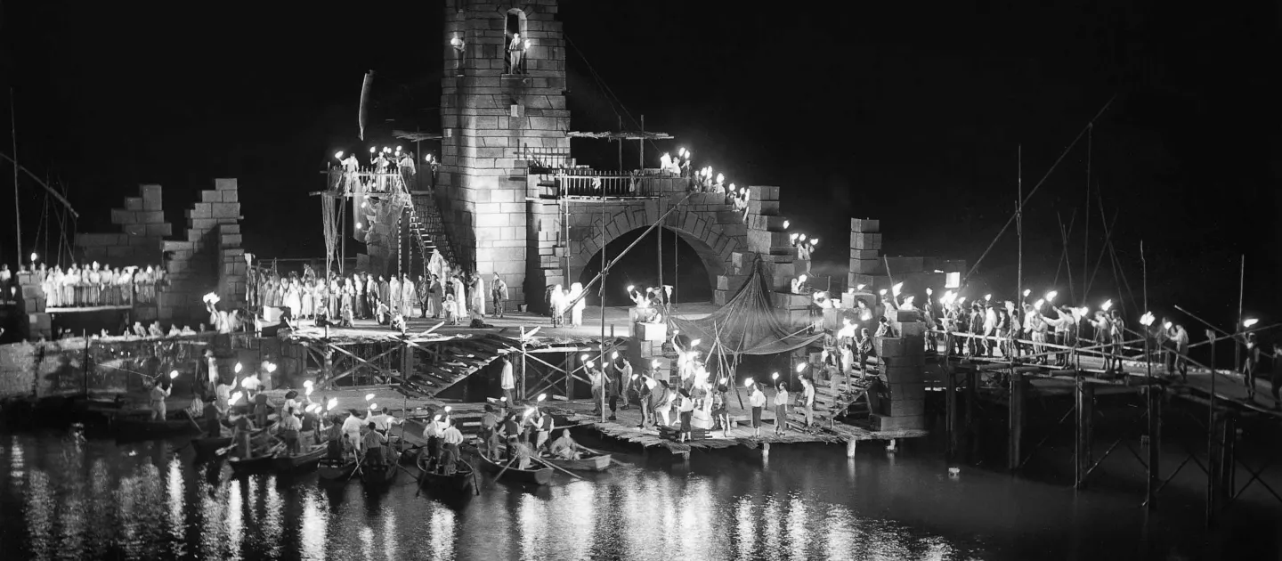 Szene aus der Zigeunerbaron, 1951 auf der Seebühne, viele Menschen mit Fackeln in der Szene, das Set besteht aus einem höheren Turm und Mauern 