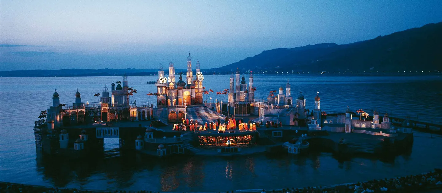 Szene aus "Tausendundeine Nacht", 1978 auf der Seebühne, mehrere miteinander verbundene Häusergruppen mit orientalischen Gestaltungselementen prägen das Bühnenbild, zentral im Bild ist eine Gruppe von Darstellenden versammelt