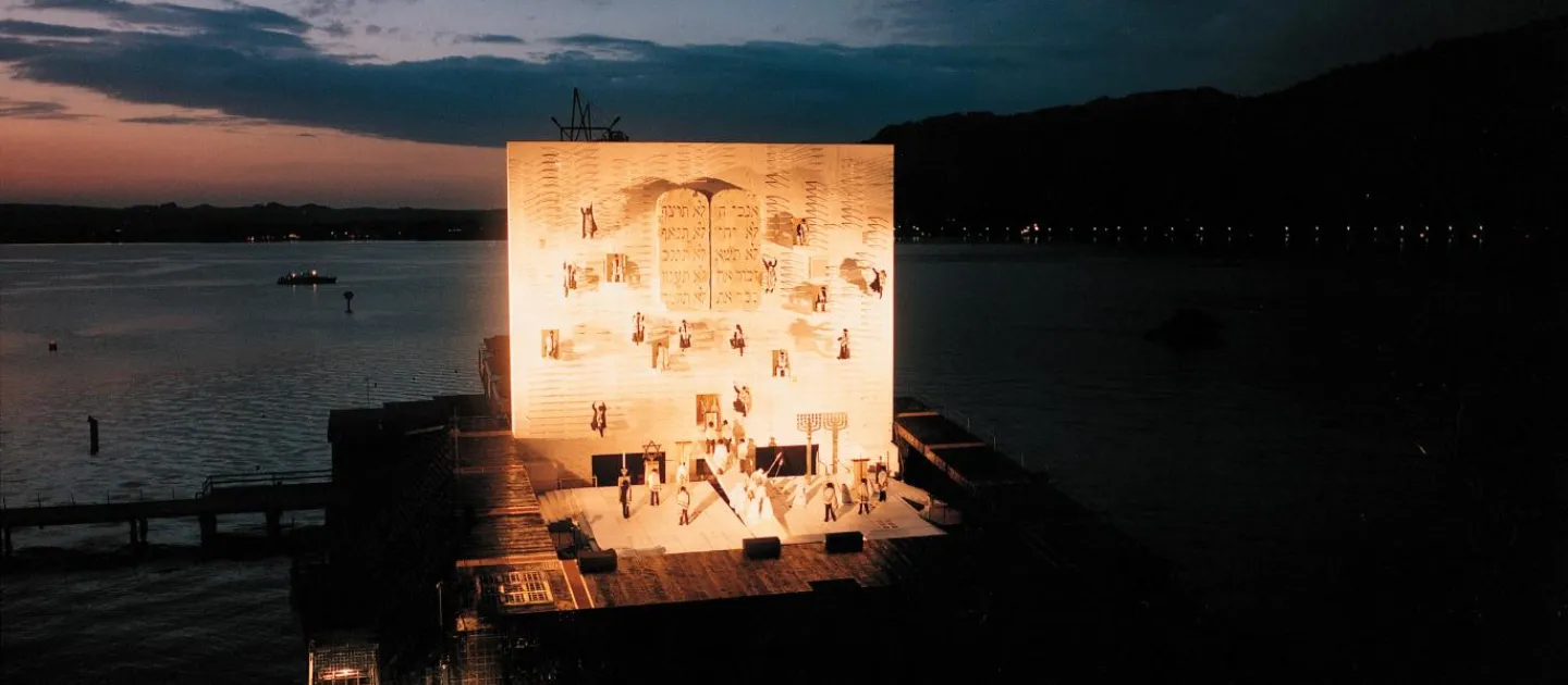 Szene aus "Nabucco", 1993 auf der Seebühne, große Wand mit biblischen Symbolen und Schriftzeichen, auf der Bühne weitere haptische Symbole und kostümierte Darstellende