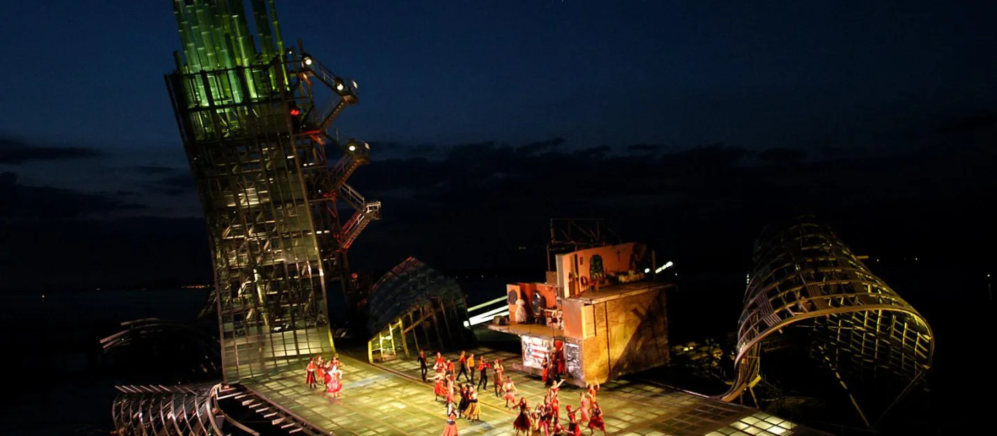 Szene aus "West Side Story", 2004 auf der Seebühne, gebogene Metallkonstruktionen ragen in den Himmel, auf der flachen Bühnenfläche viele kostümierte Darstellende