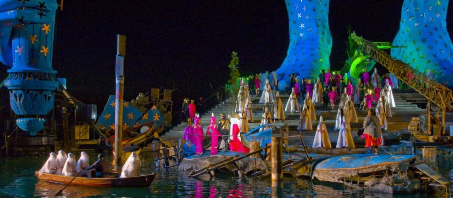 Szene aus "Aida", 2009 auf der Seebühne, große, blaue Bühnenkulisse mit Treppen und einem Boot im Wasser, viele kostümierte Darstellende