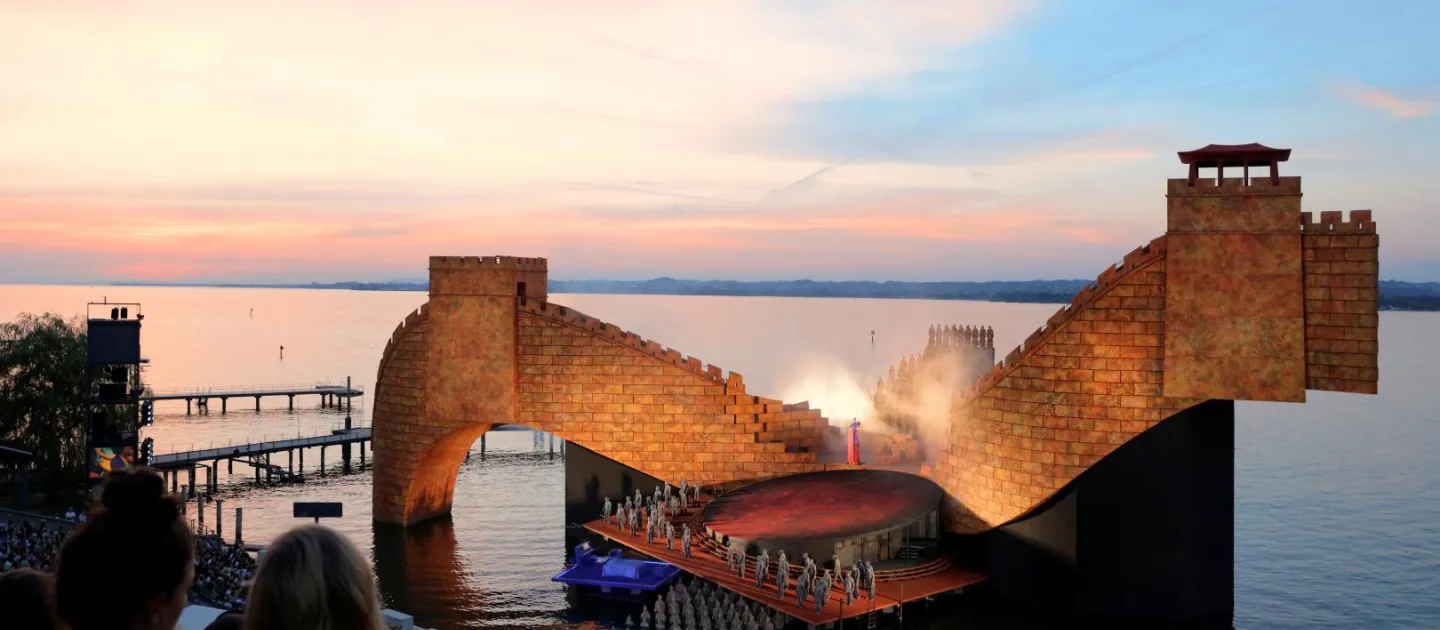Szene aus "Turandot", 2016 auf der Seebühne, gebogener Steinbogen im Hintergrund, im Vordergrund mehrere kostümierte Darstellende