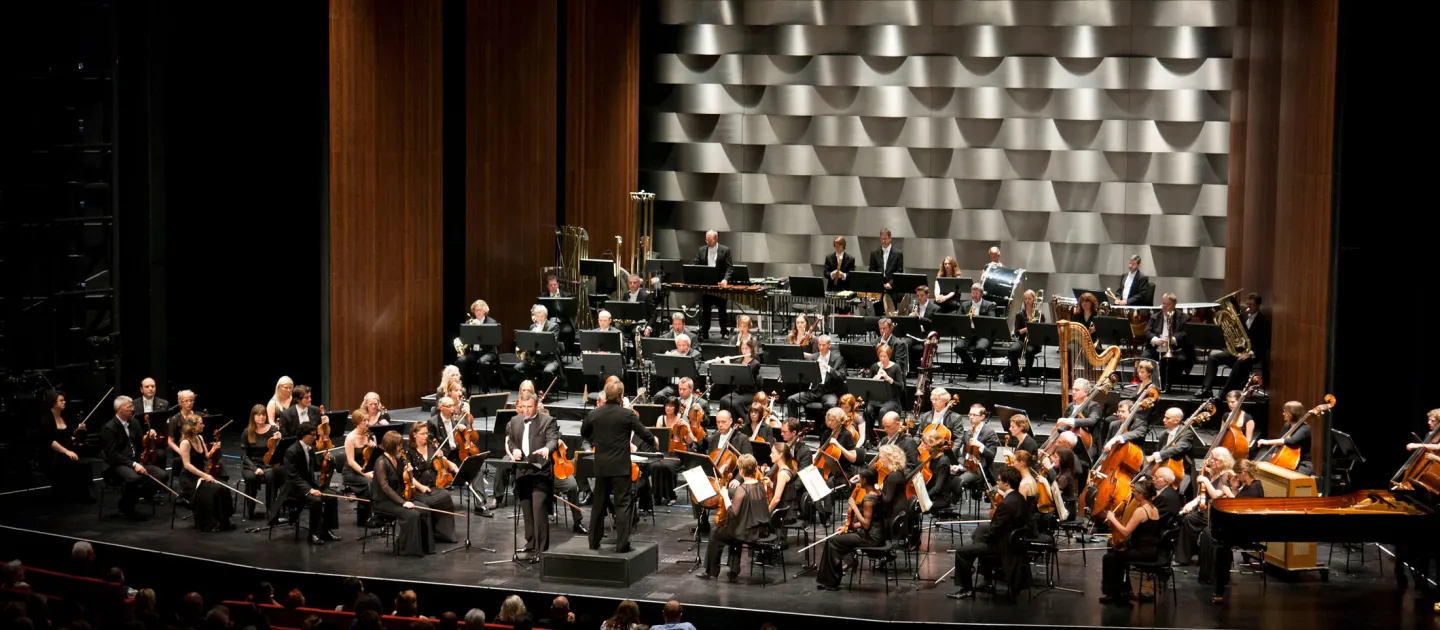 Szene aus "Hallé Orchestra Manchester", 2011 im Festspielhaus, Orchester mit Dirigent zentral vorne auf der Bühne, davor das Publikum