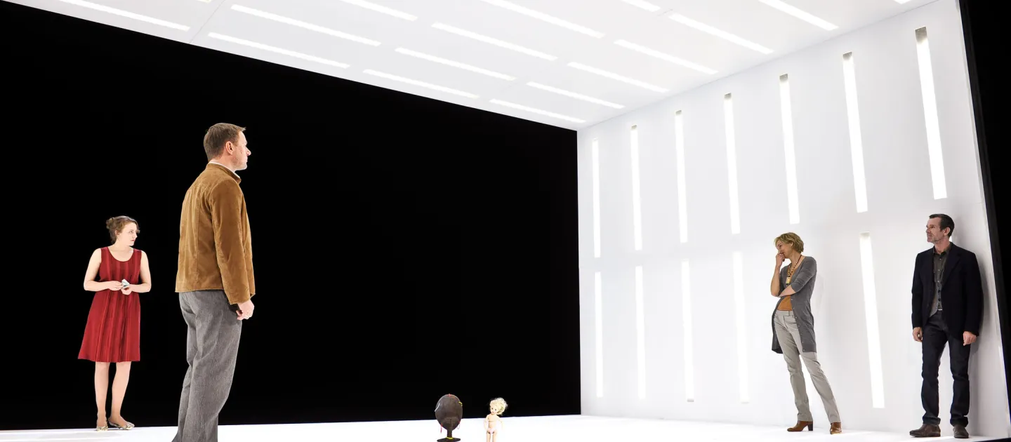 Szene aus "Peggy Pickit sieht das Gesicht Gottes", 2011 im Theater am Kornmarkt, vier kostümierte Darstellende in einem weißen Kubus ohne Vorder- und Rückwand, je zwei links und rechts, mittig zwei kleine Figuren