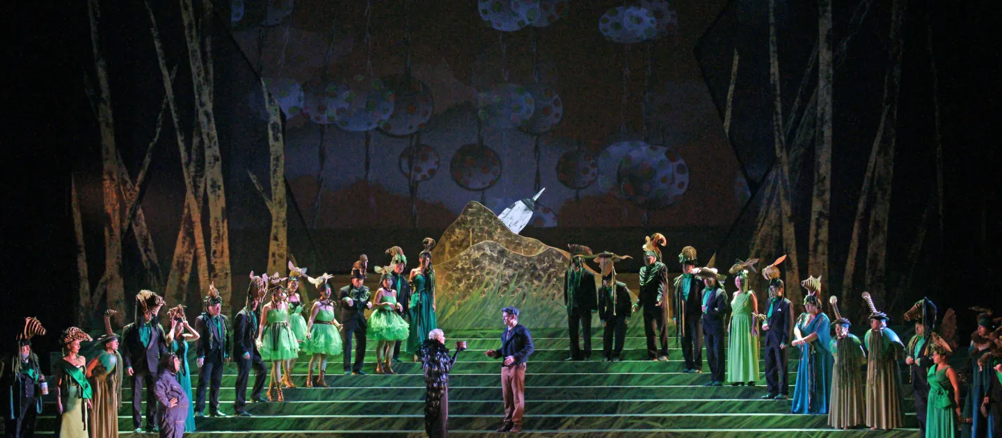 Szene aus "Le Rossignol / L’Hirondelle inattendue", 2014 im Festspielhaus, mehrere kostümierte Darstellende auf einer Treppe, aufsteigend links und rechts angeordnet, Waldkulisse im Hintergrund, zentral zwei Personen