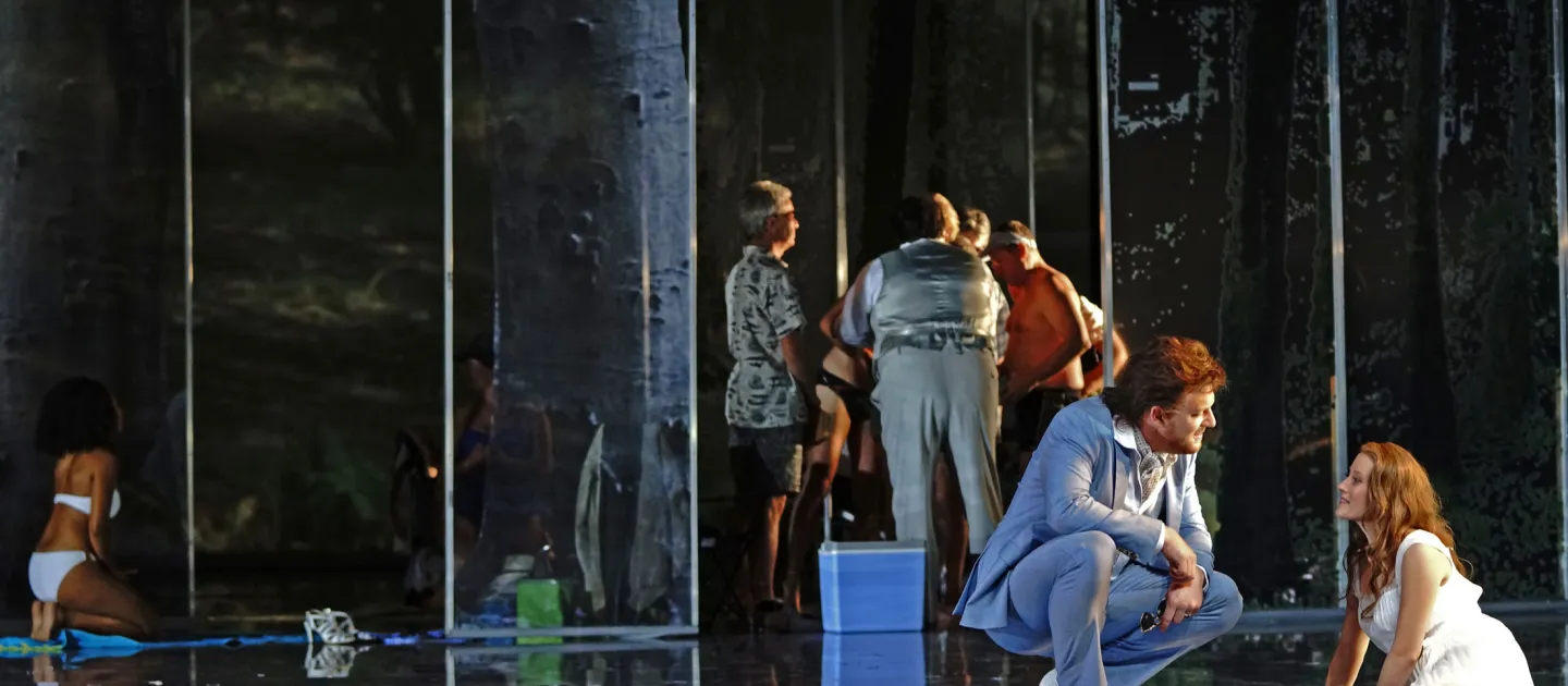 Szene aus "Geschichten aus dem Wiener Wald", 2014 im Festspielhaus, mehrere kostümierte Darstellende, im Vordergrund zwei Personen – eine sitzt, die andere in der Hocke –, im Hintergrund mehrere Personen gruppiert