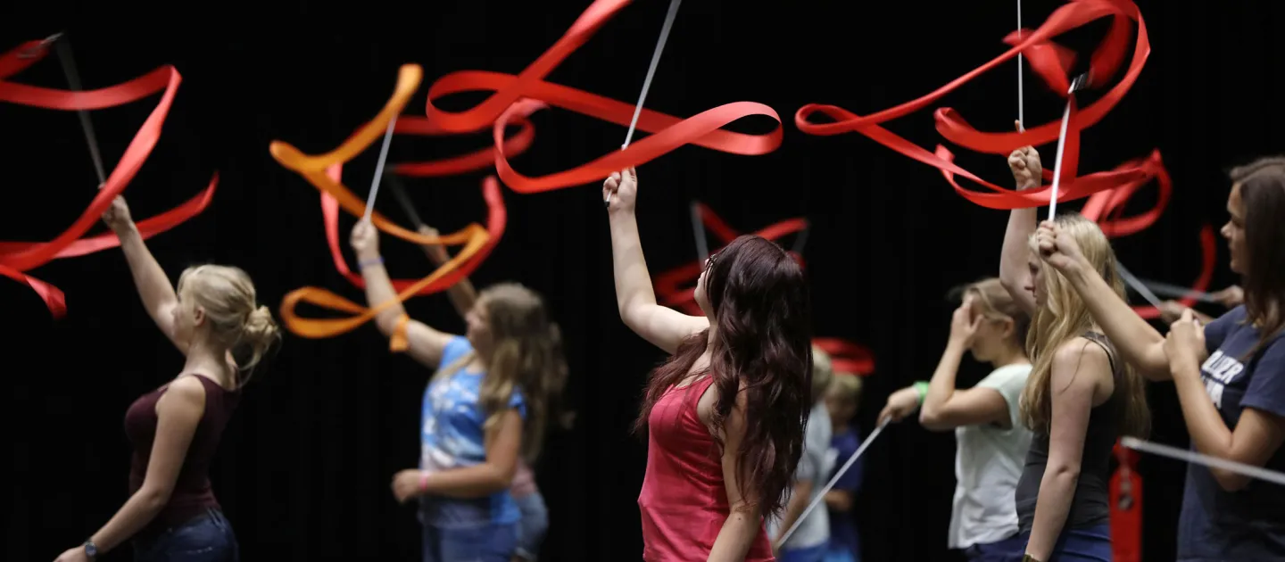 Szene aus "Crossculture", 2015 an diversen Spielorten, mehrere junge Personen bewegen rote Bänder in der Luft