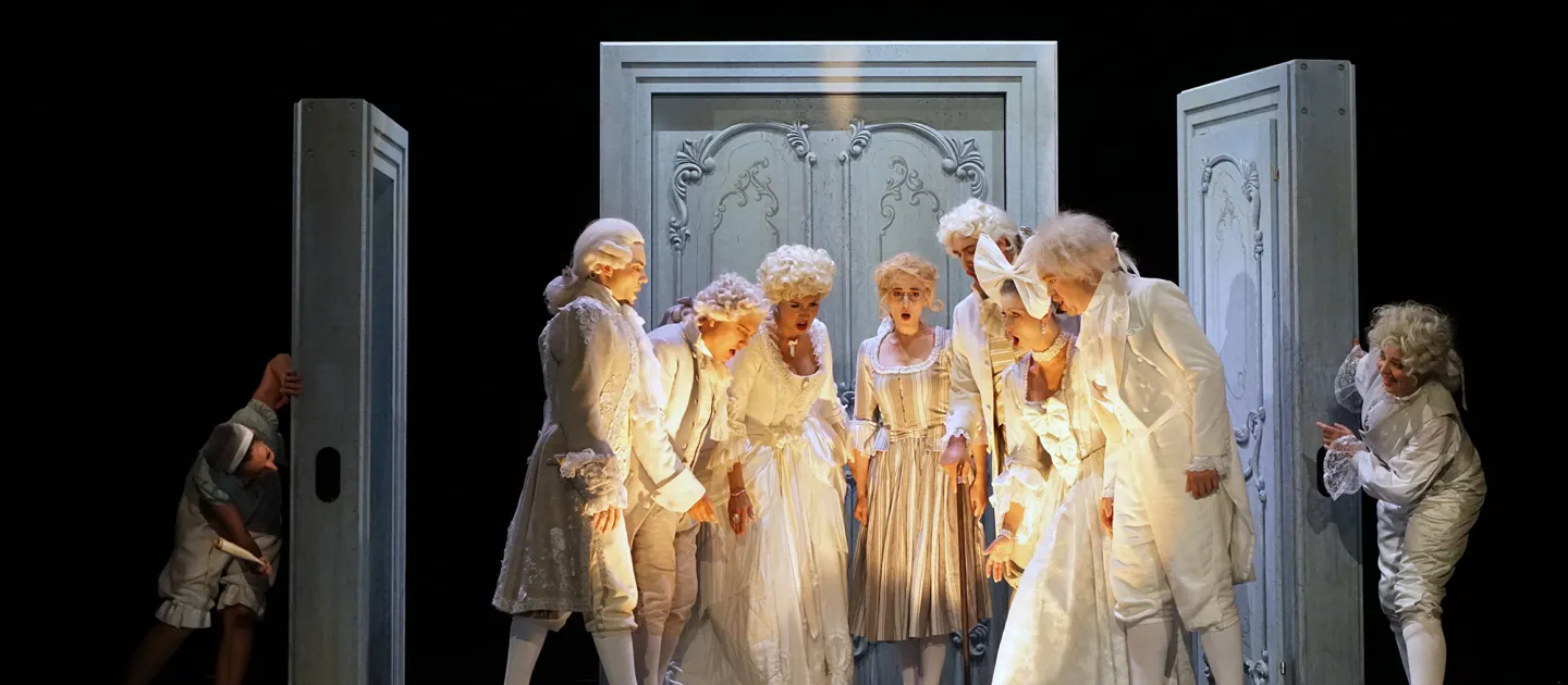 Szene aus "Die Hochzeit des Figaro", 2017 im Theater am Kornmarkt, neun kostümierte Darstellende auf der Bühne, sieben zentral, umgeben von drei großen, verzierten Türrahmen