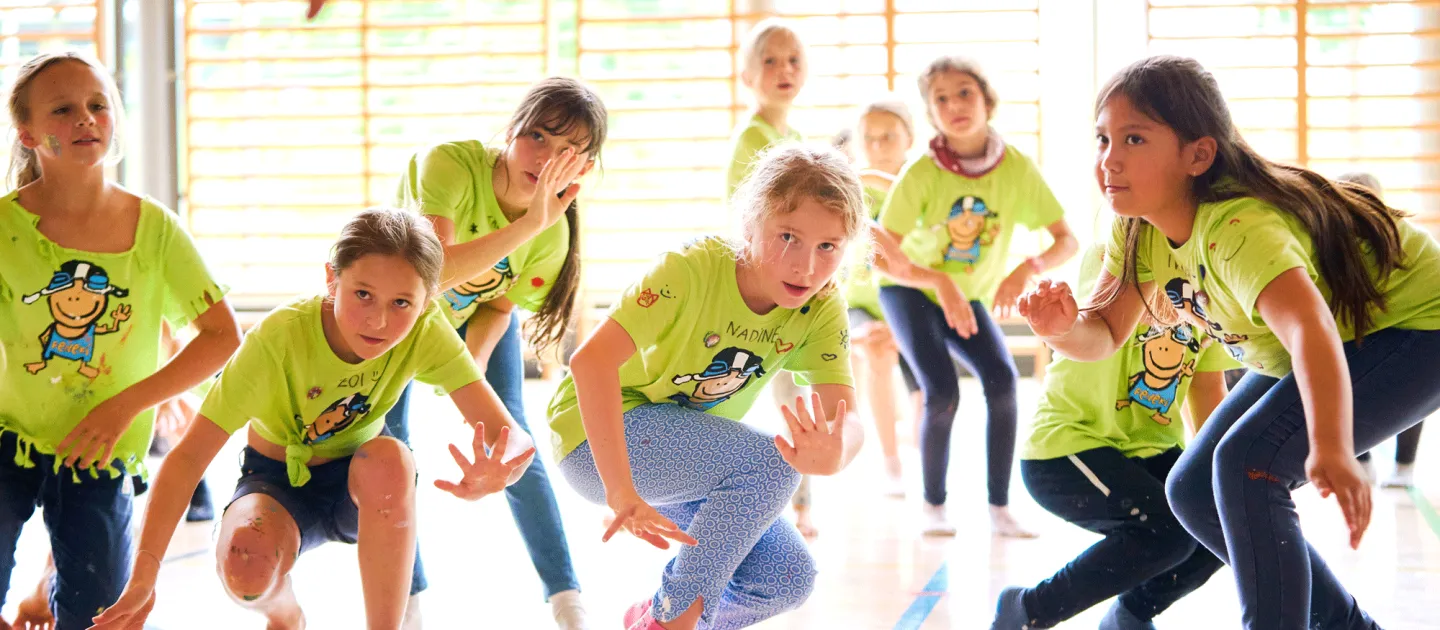 Szene aus "Crossculture", 2021, diverse Spielorte, Kinder in grünen T-Shirts in Bewegung