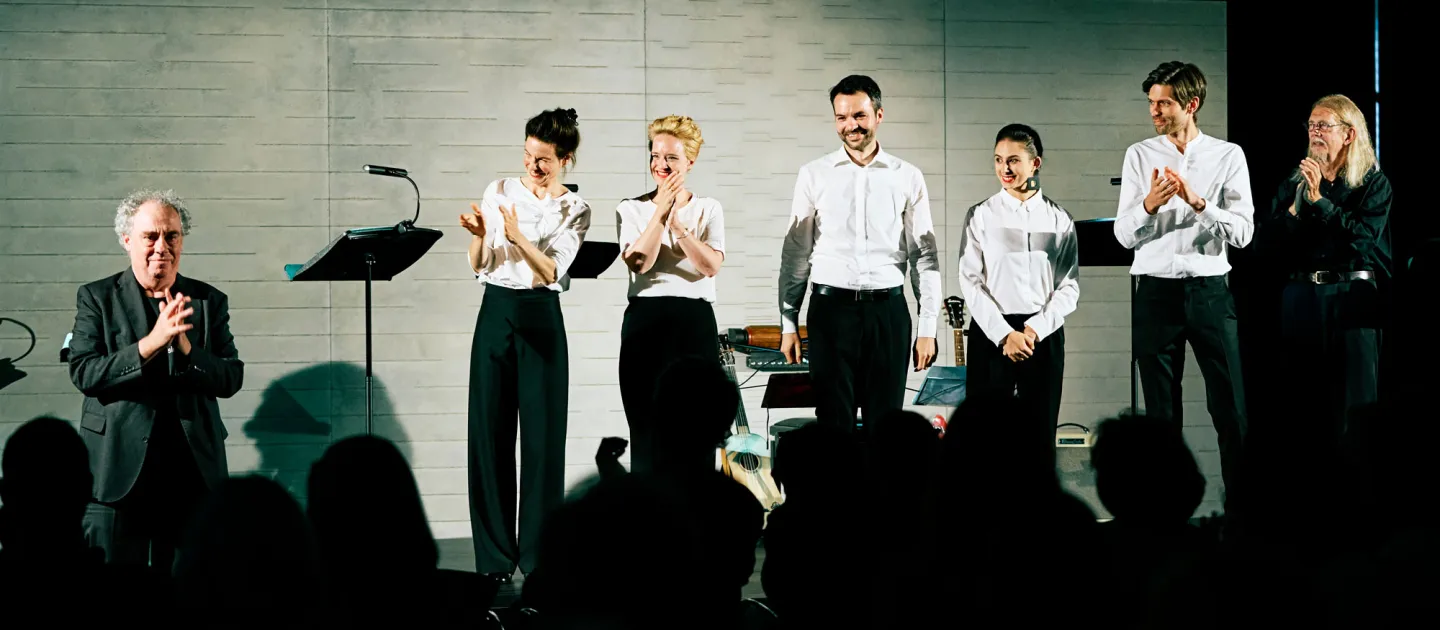 Szene aus "Konzert im KUB", 2021 im Kunsthaus im KUB, sieben Personen in formeller Kleidung, zwei davon in dunkler Kleidung, Publikum im Vordergrund