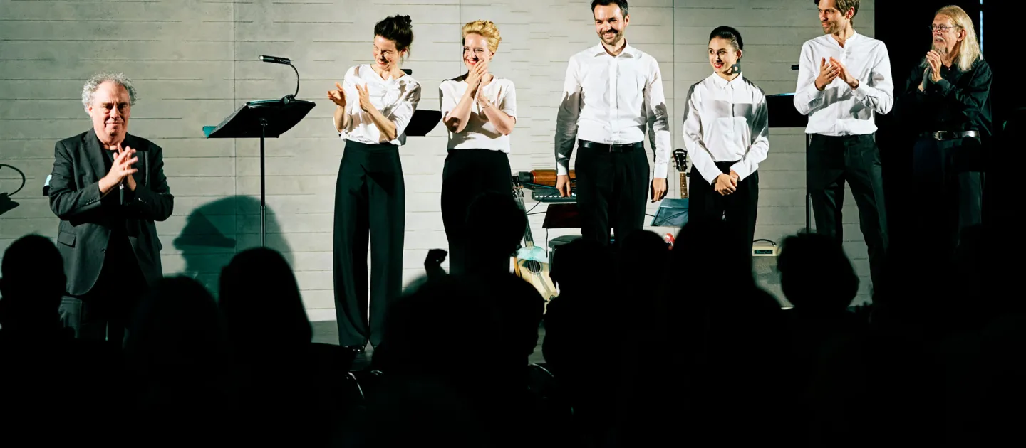 Szene aus "Konzert im KUB", 2021 im Kunsthaus im KUB, sieben Personen in formeller Kleidung, zwei davon in dunkler Kleidung, Publikum im Vordergrund