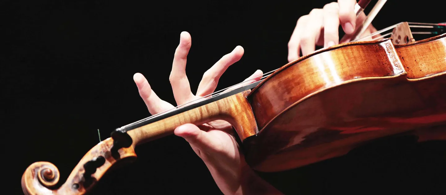 Detailaufnahme Geige, rechte Hand setzt den Bogen an, linke Hand greift den Hals des Instruments