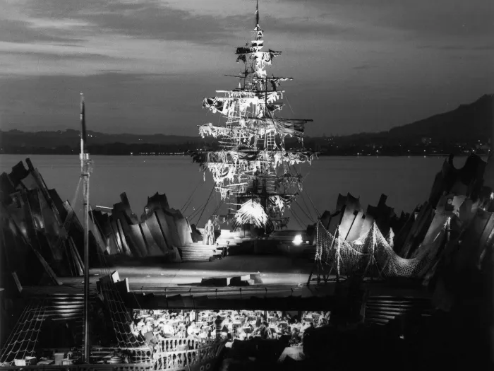 Szene aus "Der fliegende Holländer", 1973 auf der Seebühne, zentrale, leere Bühnenfläche ist von spitzen Felsen umgeben, im Hintergrund schließt mittig ein beleuchtetes Schiff an