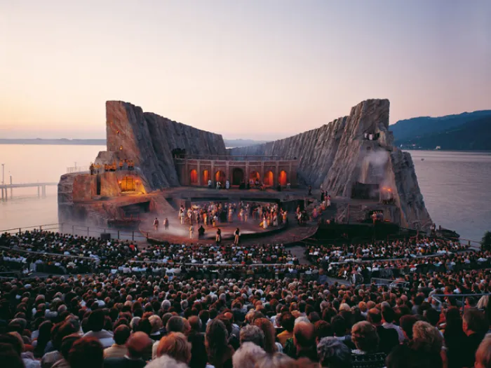 Szene aus "Carmen", 1991 auf der Seebühne, zweistöckiges Bühnenbild, Felsenlandschaft, seitlich hohe Felsen, mittig ein verbindender Gang, untere Ebene mit mehreren kostümierten Darstellenden