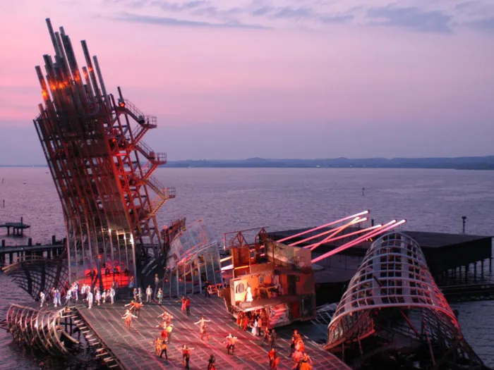 Szene aus "West Side Story", 2003 auf der Seebühne, gebogene Metallkonstruktionen ragen in den Himmel, auf der flachen Bühnenfläche viele kostümierte Darstellende
