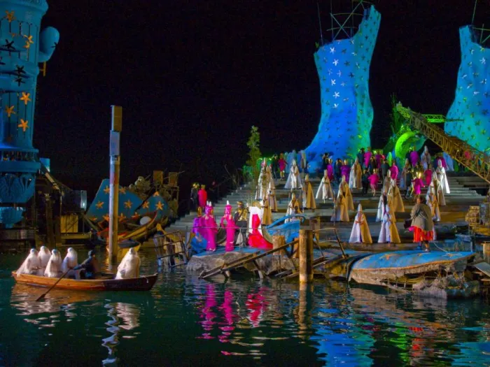 Szene aus "Aida", 2009 auf der Seebühne, große, blaue Bühnenkulisse mit Treppen und einem Boot im Wasser, viele kostümierte Darstellende