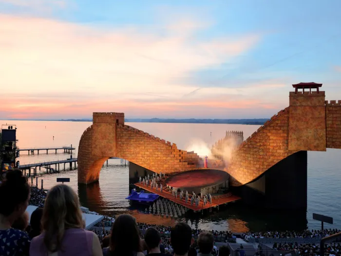 Szene aus "Turandot", 2016 auf der Seebühne, gebogener Steinbogen im Hintergrund, im Vordergrund mehrere kostümierte Darstellende