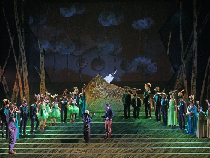 Szene aus "Le Rossignol / L’Hirondelle inattendue", 2014 im Festspielhaus, mehrere kostümierte Darstellende auf einer Treppe, aufsteigend links und rechts angeordnet, Waldkulisse im Hintergrund, zentral zwei Personen