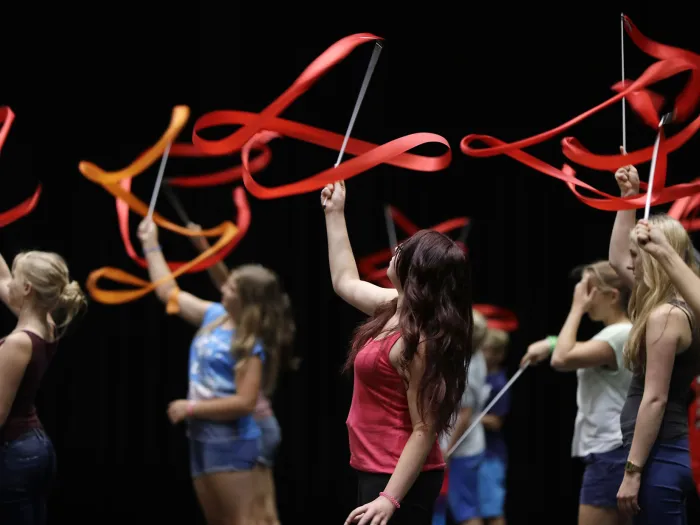 Szene aus "Crossculture", 2015 an diversen Spielorten, mehrere junge Personen bewegen rote Bänder in der Luft