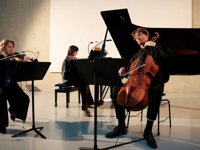 Szene aus "Konzert im KUB", 2016 im Kunsthaus Bregenz, drei Musiker:innen spielen die Instrumente Violine, Klavier und Cello 