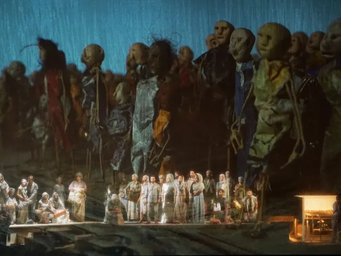 Szene aus "Moses in Ägypten", 2017 im Festspielhaus, im Vordergrund kostümierte Darstellende auf der Bühnenfläche, im Hintergrund übergroße Puppen