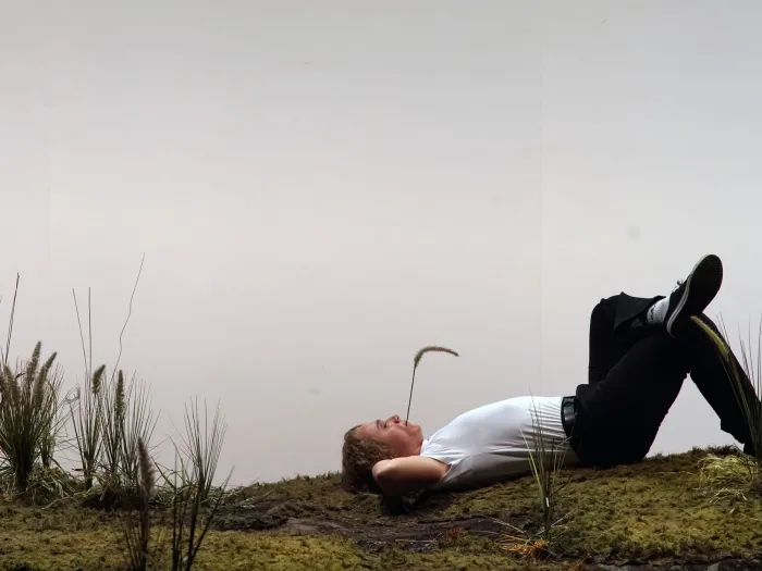 Szene aus "Eugen Onegin", 2019 im Theater am Kornmarkt, Mann mit Grashalm im Mund liegt auf dem Rücken, ein Bein angewinkelt