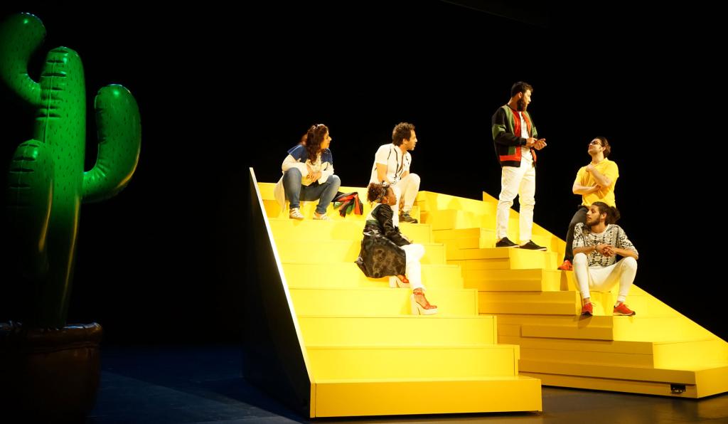 The Situation - Theater am Kornmarkt - Bregenzer Festspiele - SchauspielerInnen auf gelber Treppe mit Kaktus im Hintergrund